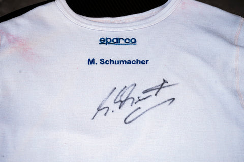 Ferrari team shirt signed by Michael Schumacher, racing memorabilia. / Maglia del team Ferrari autografata da Schumacher, memorabilia da corsa